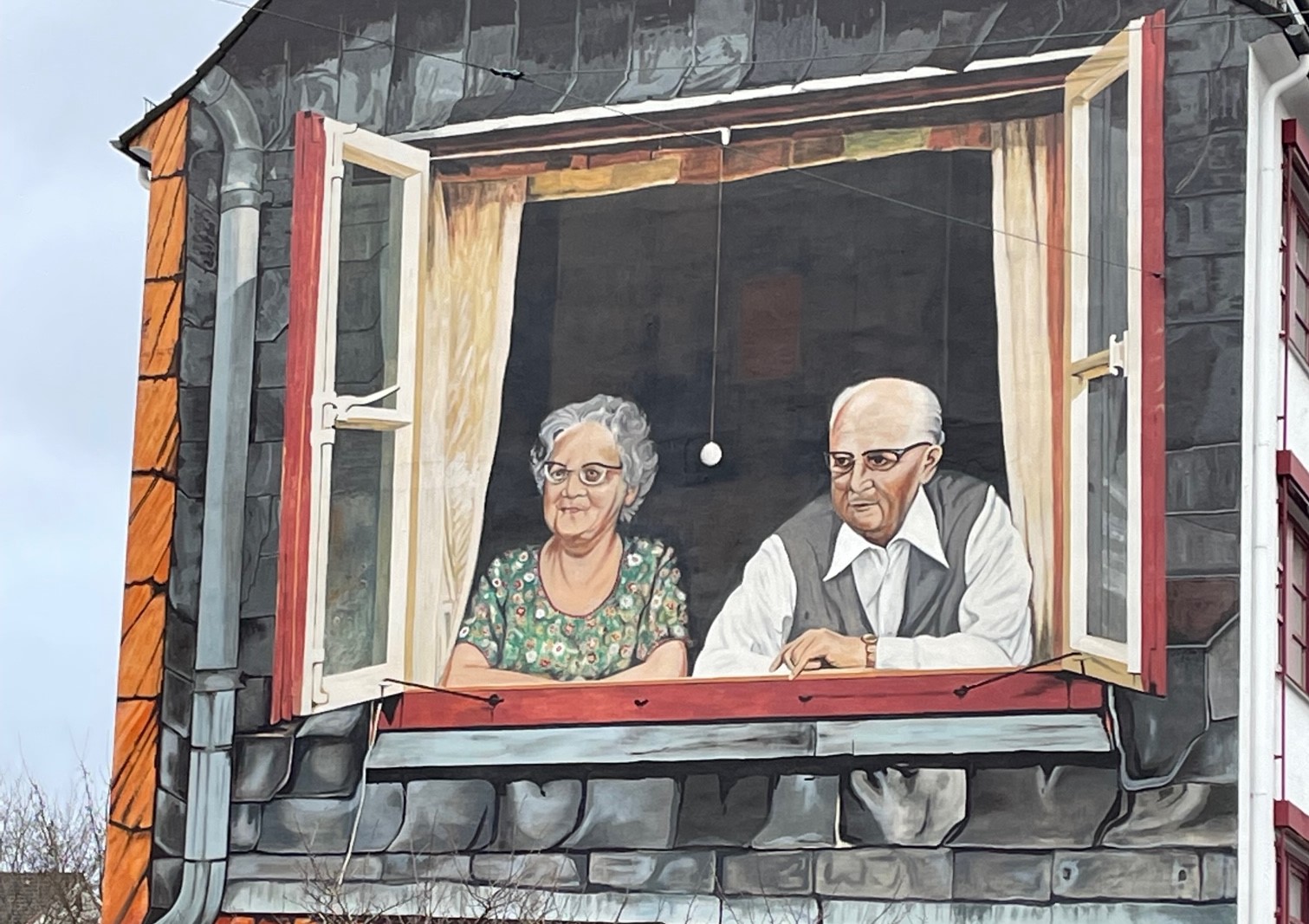 Bremer Hausfassade mit gemaltem Bild eines älteren Ehepaares, das aufgestützt auf die Fensterbank freundlich aus dem Fenster schaut