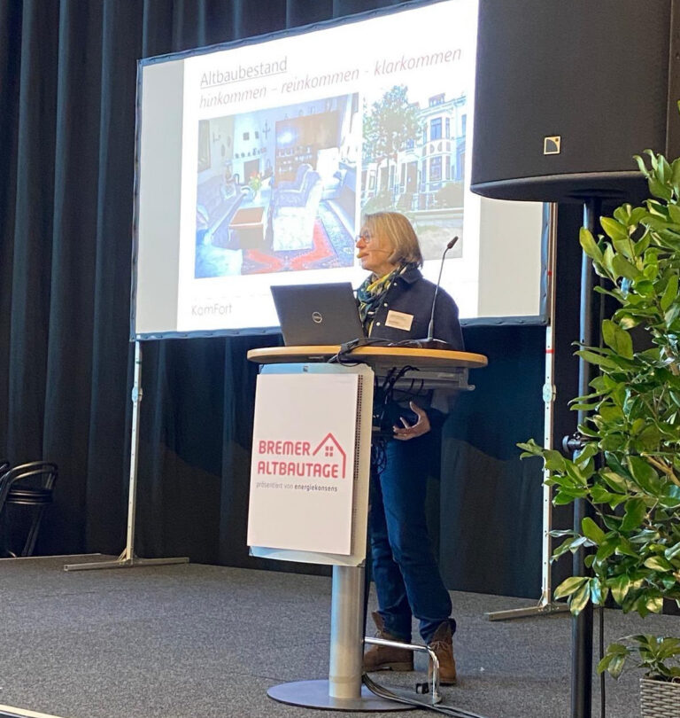 Ulrike Brilling auf einer Bühne. Im Hintergrund ist eine Folie zu sehen.