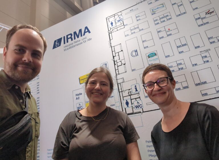 Isabelle Barthelmeß, Carolina Bergedieck und Simon Breul stehen vor dem Messeplan der IRMA 2026.